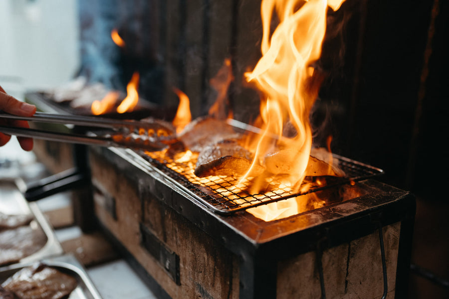 Shiok BBQ 厨师在新加坡现场烧烤站的明火上烧烤