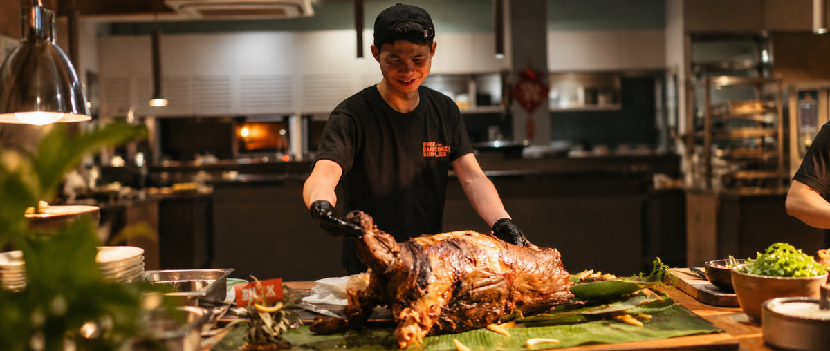 A Shiok BBQ chef carving a whole spit roasted lamb at a live station in Singapore
