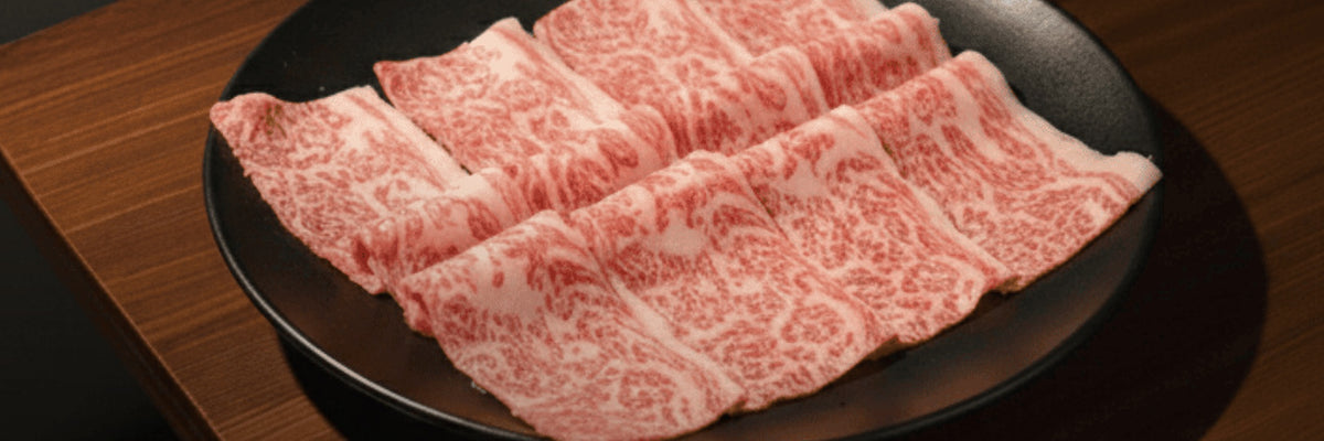 Thinly sliced marbled beef on a dark plate from the Shiok BBQ butcher shop in Singapore