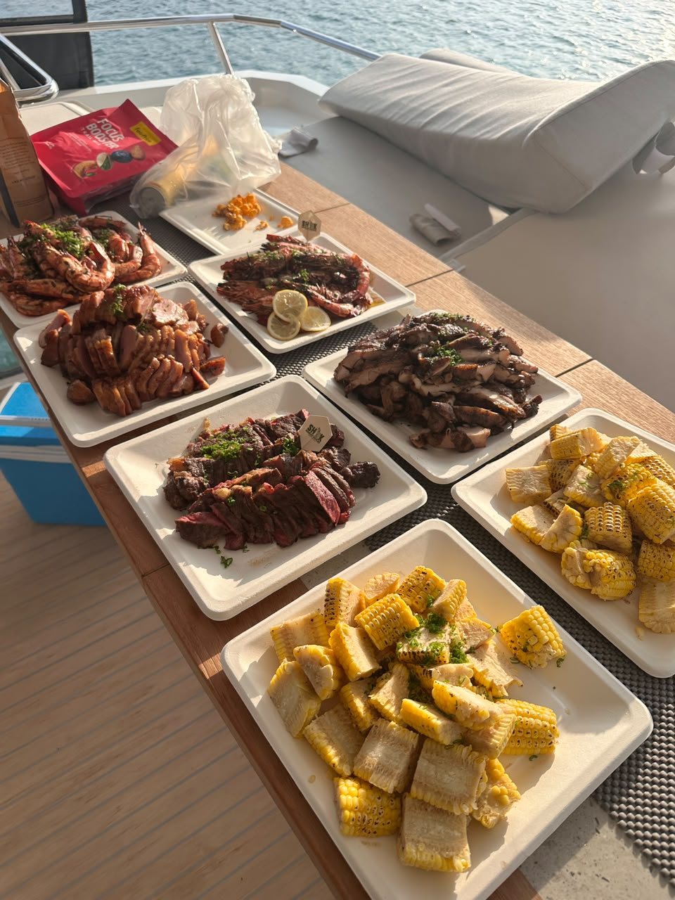 新加坡游艇甲板上，Shiok BBQ 助手套餐的整套烧烤，有肉类、虾和玉米
