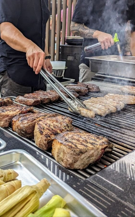 Shiok BBQ chef working the grill at a live station event in Singapore, second chef finishing with a torch