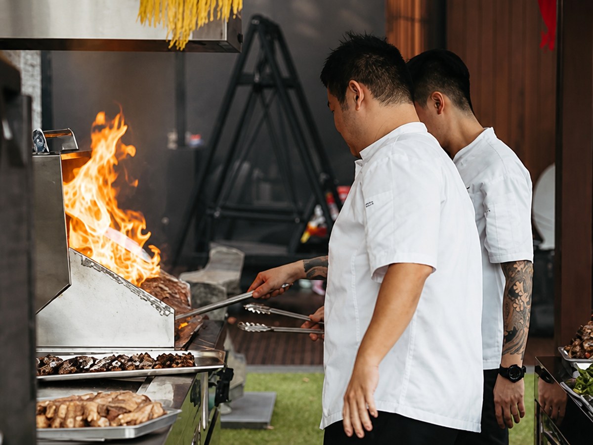 Two Shiok BBQ chefs working an open flame live station, Singapore